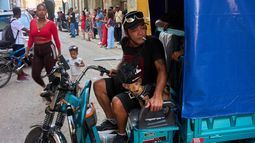 Un hombre maniobra su triciclo eléctrico junto a su perro pequeño en La Habana, Cuba, el miércoles 29 de julio de 2026. (Foto AP/Ramon Espinosa)