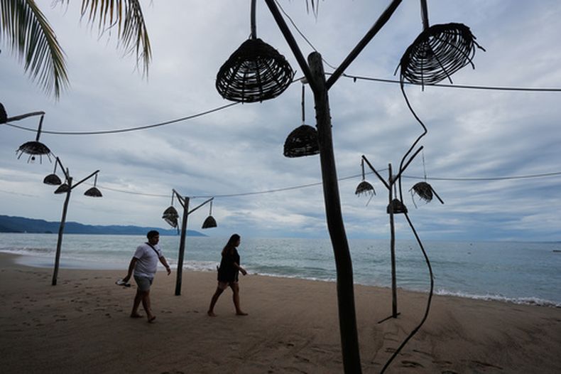 Personas caminan por la playa tras el paso del huracán Simon en Puerto Vallarta, México, el lunes 12 de octubre de 2026. (Foto AP/Fernando Llano)