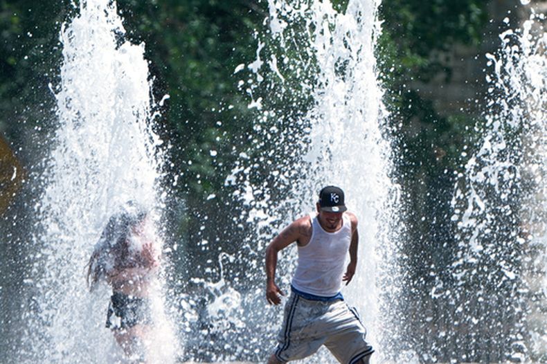 Varias personas se refrescan en una fuente durante una ola de calor, el lunes 29 de junio de 2026, en Kansas City, Kansas. (AP Foto/Charlie Riedel)