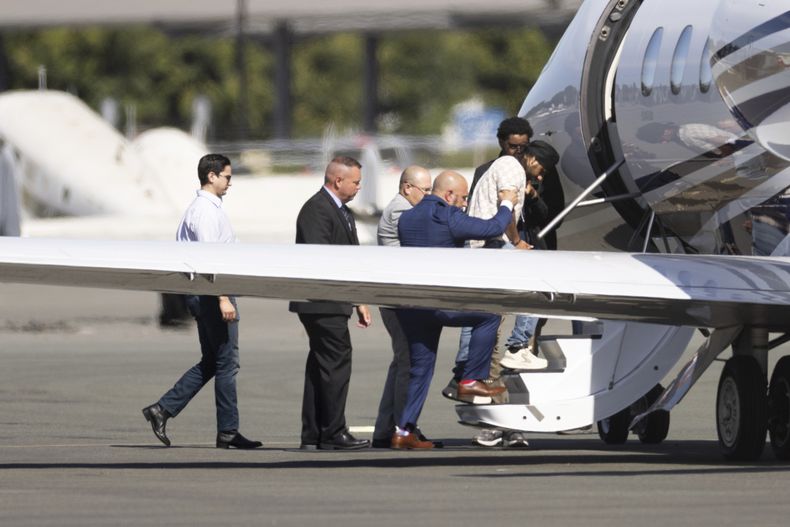 Harjinder Singh es escoltado hacia un avión por el vicegobernador de Florida, Jay Collins, y policías, el jueves 21 de agosto de 2025, en Stockton, California. (AP Foto/Benjamin Fanjoy)