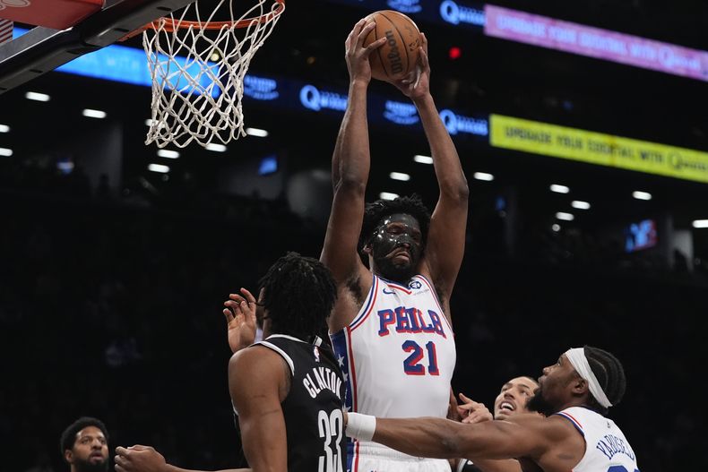 Joel Embiid, de los 76ers de Filadelfia, lucha por el control del balón con Nic Claxton (33), de los Nets de Brooklyn, durante la primera mitad de un partido de baloncesto de la NBA, el sábado 4 de enero de 2025, en Nueva York. (AP Foto/Frank Franklin II)