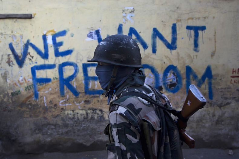 Un soldado paramilitar de la India frente a una pared con graffiti en Srinagar, Cachemira, el 29 de agosto del 2016. (AP foto/Dar Yasin)