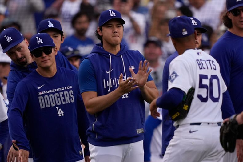 El pelotero de los Dodgers de Los Ángeles, Mookie Betts (derecha), es felicitado por Shohei Ohtani (centro) y Yoshinobu Yamamoto después de que los Dodgers derrotaran a los Gigantes de San Francisco en un partido de béisbol, el domingo 20 de septiembre de 2026, en Los Ángeles. (Foto AP/Mark J. Terrill)