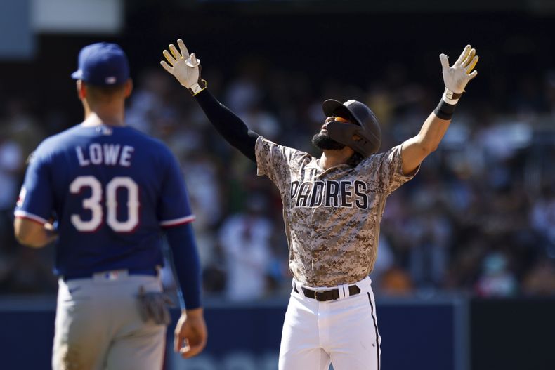 Fernando Tatis Jr., derecha, de los Padres de San Diego, alza los brazos después de conectar un sencillo productor de una carrera frente a los Rangers de Texas en la novena entrada del juego de béisbol, el domingo 30 de julio de 2023, en San Diego. (AP Foto/Derrick Tuskan)