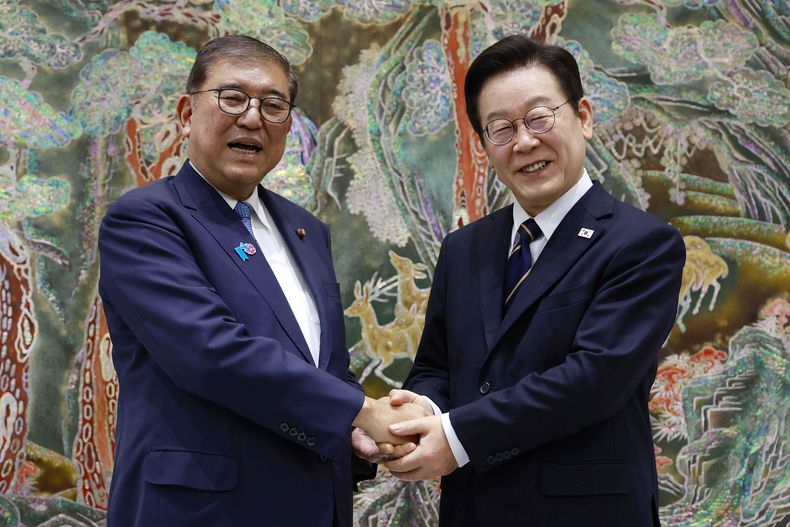 El presidente de Corea del Sur, Lee Jae Myung, a la derecha, estrecha la mano del primer ministro japonés, Shigeru Ishiba, a la izquierda, durante una reunión en Busan, Corea del Sur, el martes 30 de septiembre de 2025. (Yonhap via AP)
