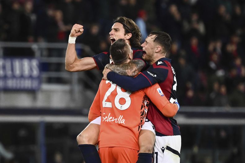 Riccardo Calafiori (arriba), Lukasz Skorupski (izquierda) y Sam Beukema, de Bologna, festejan la victoria sobre la Lazio en un partido de la Serie A italiana, el viernes 3 de noviembre de 2023 (Massimo Paolone/LaPresse via AP)