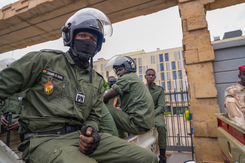 Policías nigerinos sentados ante las oficinas de aduanas en Niamey, Níger, el lunes 21 de agosto de 2023. (AP Foto/Sam Mednick)