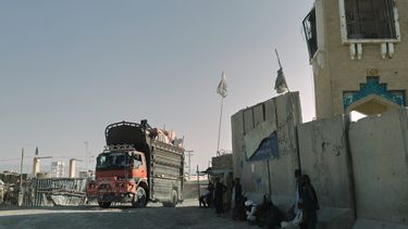 Gente esperando cerca de una puerta cerrada en el paso fronterizo de Spin Boldak con Pakistán, tras casi dos semanas de cierre de frontera por enfrentamientos entre fuerzas afganas y paquistaníes, en la provincia de Kandahar, Afganistán, el jueves 23 de octubre de 2025. (AP Foto/Sibghatullah)