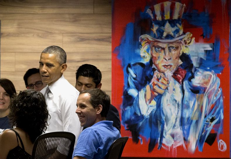 El presidente Barack Obama conversa con trabajadores junto a una pintura del "T&iacute;o Sam" el jueves 3 de julio de 2014, en Washington. (Foto AP/Jacquelyn Martin)