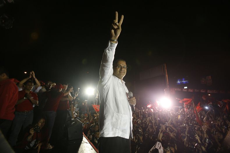 ARCHIVO - Mauricio Funes, candidato presidencial del partido Frente de Farabundo Martí de Liberación Nacional (FMLN), hace el gesto de victoria a sus seguidores durante un discurso de celebración por su victoria electoral en San Salvador, el 15 de marzo de 2009. (AP Foto/Dario Lopez-Mills, Archivo)