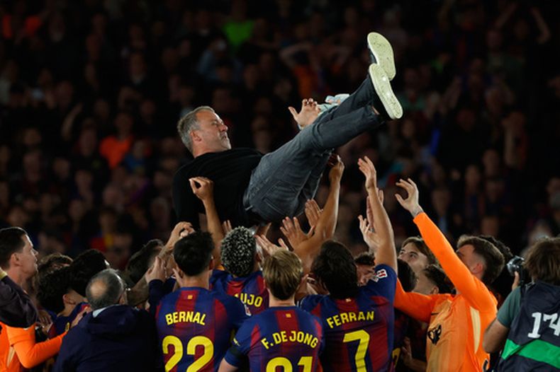 Hansi Flick, entrenador del Barcelona, es lanzado al aire por sus jugadores después de la conquista del título de La Liga de España tras la victoria sobre el Real Madrid, lo que aseguró el campeonato para Barcelona, el domingo 10 de mayo de 2026, en Barcelona, España. (AP Foto/Joan Monfort)
