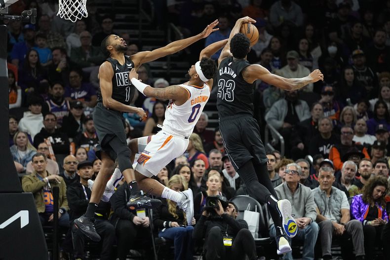 Nic Claxton (33), de los Nets de Brooklyn, bloquea un tiro de Jordan Goodwin (0), de los Suns de Phoenix, durante la segunda mita del juego de baloncesto de la NBA, el miércoles 13 de diciembre de 2023, en Phoenix. (AP Foto/Matt York)