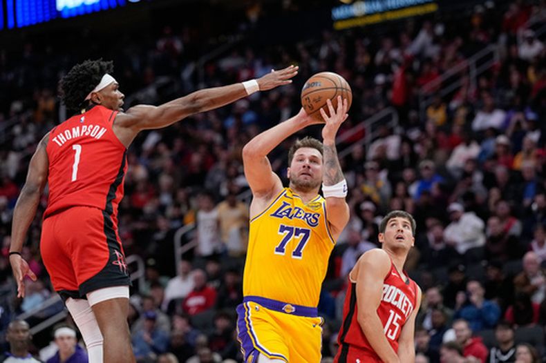 Luka Doncic (77), de los Lakers de Los Ángeles, dispara mientras Amen Thompson (1), de los Rockets de Houston, defiende durante la primera mitad del juego de baloncesto de la NBA, el lunes 16 de marzo de 2026, en Houston. (AP Foto/David J. Phillip)