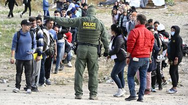 Un agente de la Patrulla Fronteriza da indicaciones a solicitantes de asilo para que esperen en la frontera de Estados Unidos con México, cerca de Tijuana, México, el lunes 8 de mayo de 2023, en San Diego. (AP Foto/Denis Poroy)