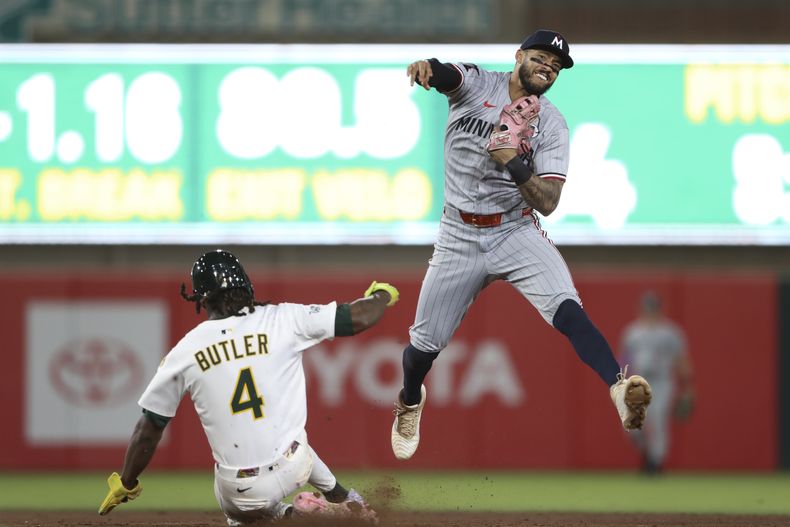 Carlos Correa, deracha, de los Mellizos de Minnesota, lanza a primera para completar un doble play frente a los Atléticos durante la novena entrada del juego de béisbol de Grandes Ligas, el lunes 2 de junio de 2025, en West Sacramento, California. (AP Foto/Scott Marshall)