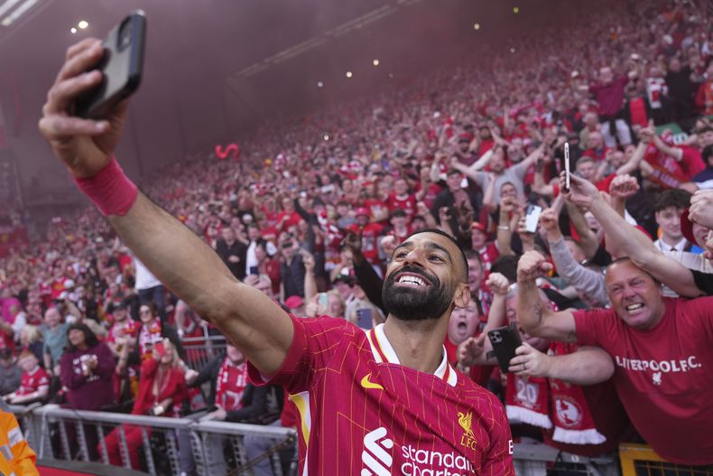 Mohamed Salah, del Liverpool, celebra tomándose una selfie después de ganar el partido de fútbol de la Liga Premier inglesa entre Liverpool y Tottenham Hotspur y asegurar el título de la Liga Premier en Anfield en Liverpool, Inglaterra, el domingo 27 de abril de 2025. (AP Foto/Jon Super)