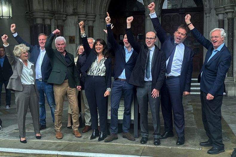 Colin Berminghan, tercero desde la izquierda, y Alex Pabon, cuarto desde la derecha, celebran junto con partidarios, incluyendo el legislador David Davis (al final a la derecha) y abogados afuera del tribunal en Londres luego que sus condenas fueron anuladas, el 7 de octubre de 2026. (Jack Hudson/PA via AP)