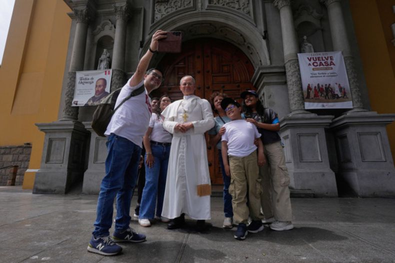 Una familia se toma una selfi con una estatua de tamaño natural del papa León XIV, expuesta frente a una iglesia en el barrio de Barranco, en Lima (Perú), el martes 13 de octubre de 2026, un mes antes de la visita del papa al país. (Foto AP/Martín Mejía)