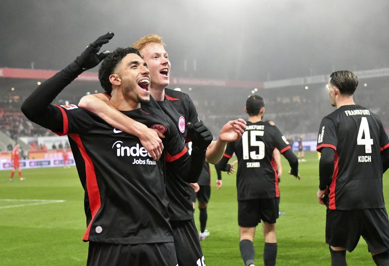 Hugo Larsson y Omar Marmoush celebran el tercer gol de Eintract Frankfurt, obra de Marmoush, ante FC Heidenheim en la Bundesliga, el domingo 1 de diciembre de 2024. (Jan-Philipp Strobel/dpa vía AP)
