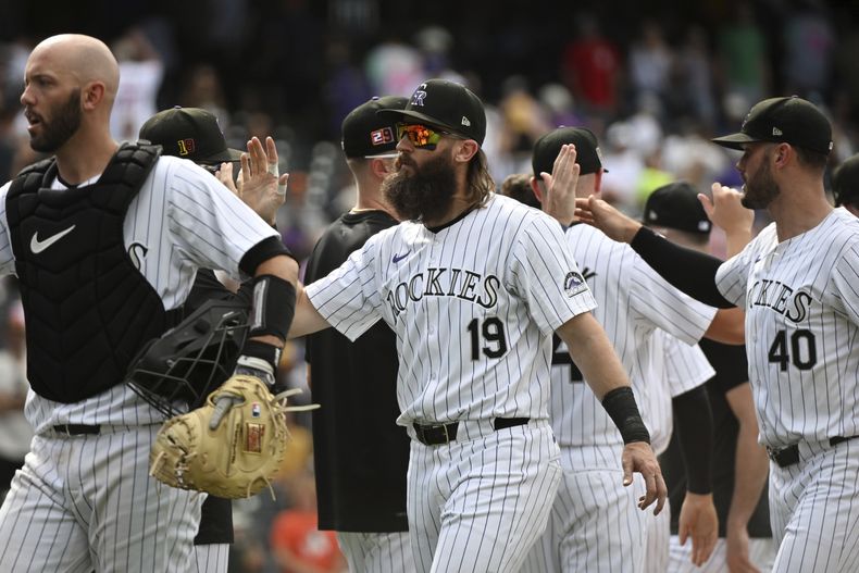 De izquierda a derecha, el receptor de los Rockies de Colorado Jacob Stallings, el bateador designado Charlie Blackmon y el lanzador relevista Tyler Kinley celebran después de un juego contra los Padres de San Diego, el domingo 18 de agosto de 2024, en Denver. (AP Foto/Geneva Heffernan)