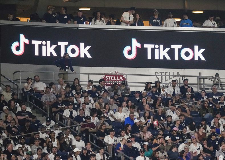 ARCHIVO - Aficionados están sentados bajo un anuncio de TikTok mientras asisten a un partido de béisbol en el Yankee Stadium, el 14 de abril de 2023, en Nueva York. (AP Foto/Frank Franklin II, Archivo)