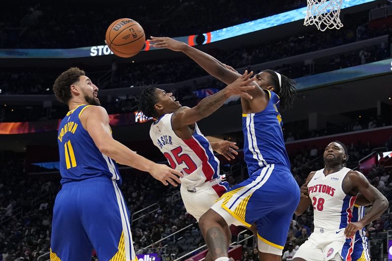 Kevon Looney, de los Warriors de Golden State, bloquea un tiro de Marcus Sasser (25), de los Pistons de Detroit, durante la primera mitad del juego de baloncesto de la NBA, el lunes 6 de noviembre de 2023, en Detroit. (AP Foto/Carlos Osorio)