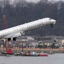 Mientras un avión de American Eagle despega, cuadrillas realizan tareas de recuperación cerca del punto en el río Potomac donde cayeron los restos de un avión comercial y un helicóptero militar que chocaron en pleno vuelo en el Aeropuerto Nacional Ronald Reagan, el jueves 6 de febrero de 2025, en Arlington, Virginia. (AP Foto/José Luis Magaña)