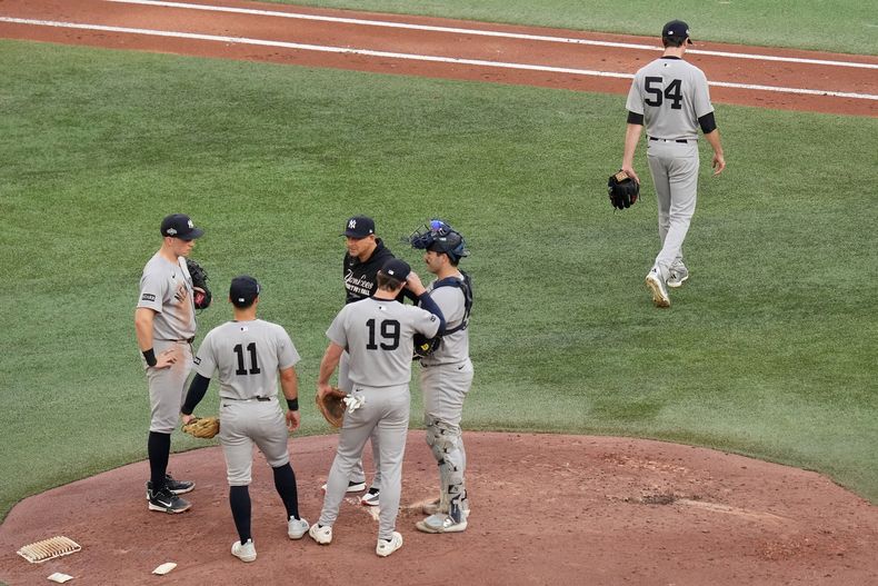 Max Fried (54), lanzador de los Yankees de Nueva York, regresa al dugout después de haber sido retirado de la loma por el manager Aaron Boone, ene l centro, durante la cuarta entrada del segundo juego de la Serie Divisional de la Liga Americana contra los Azulejos de Toronto, el domingo 5 de octubre de 2025, en Toronto. (Chris Young/The Canadian Press via AP)