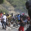 Un grupo de personas huye del gas lacrimógeno disparado por la policía para dispersar a los manifestantes que exigen a la policía y al primer ministro que actúen de inmediato contra las pandillas, en Puerto Príncipe, Haití, el lunes 19 de agosto de 2024. (AP Foto/Odelyn Joseph)