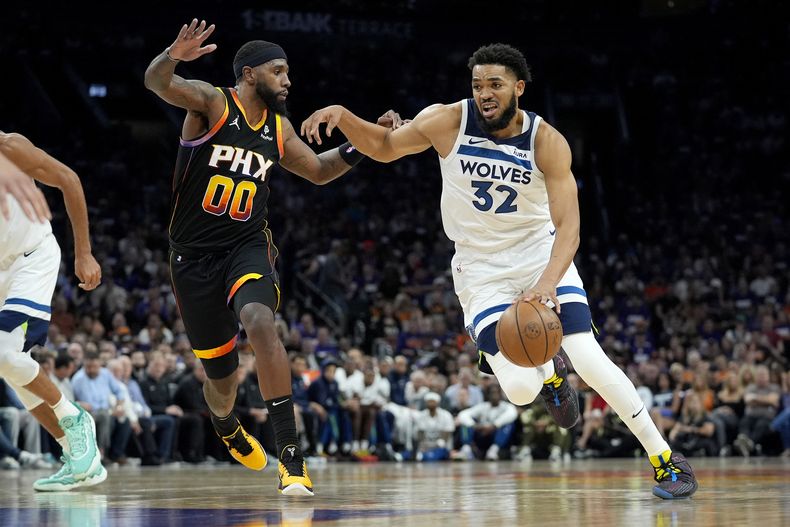 Karl-Anthony Towns (32), de los Timberwolves de Minnesota, conduce la pelota ante su rival de los Suns de Phoenix Royce ONeale durante la primera mitad del tercer juego de la primera ronda de los playoffs de la NBA, el 26 de abril de 2024, en Phoenix. (AP Foto/Matt York)