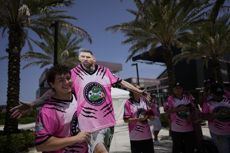 Julián Iglesias, de 19 años, sostiene una silueta de Lionel Messi, recortada en cartón, mientras un grupo de aficionados espera la llegada del astro argentino a Miami, el martes 11 de julio de 2023 an Iglesias (AP Foto/Rebecca Blackwell)