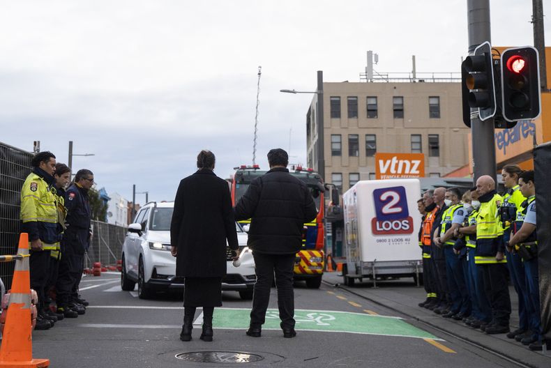 Investigadores policiales y de incendios forman una guardia de honor a la salida del primer cuerpo del hostal Loafers en Wellington, Nueva Zelanda, el jueves 18 de mayo de 2023. La policía neozelandesa detuvo el jueves a un hombre y le acusó de dos delitos de incendio provocado en relación a un incendio en un hostal de Wellington en el que murieron al menos seis personas, según indicaron las autoridades. (George Heard/New Zealand Herald via AP)
