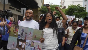 Luis Arroyo, a la izquierda, con las fotos de sus dos hijos desaparecidos, Ismael y Josué, quienes fueron vistos por última vez el pasado 8 de diciembre, tras intentar huir de un convoy militar junto a otros dos jóvenes, durante una protesta con su familia y organizaciones ante la sede de la fiscalía en Guayaquil, el lunes 23 de diciembre de 2024. (AP Foto/César Muñoz)