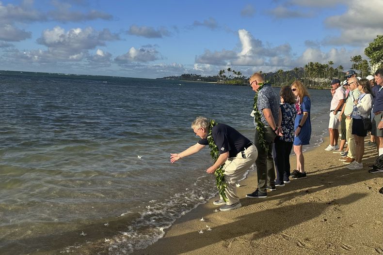Eric Murray, padre del fallecido golfista Grayson Murray, lanza una orquídea blanca al océano el martes 7 de enero de 2025, durante un homenaje en Honolulú (AP Foto/Doug Ferguson)