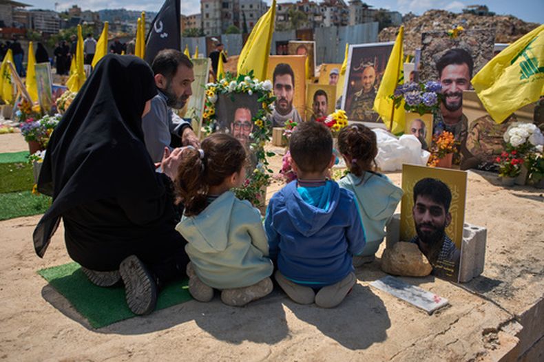 Familiares rezan en la tumba de una persona enterrada junto a combatientes de Hezbollah muertos en ataques israelíes, en un cementerio de Choueifat, Líbano, el lunes 13 de abril de 2026. (Foto AP/Emilio Morenatti)