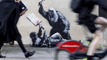 Fotografía sin fecha publicada por Banksy de la nueva obra de arte del artista que retrata a un juez golpeando a un manifestante con un mazo en los Tribunales Reales de Justicia de Londres. (Banksy via AP)