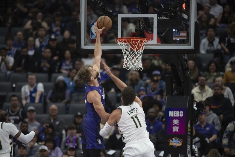 El alero de los Kings de Sacramento Domantas Sabonis anota superando al pívot de los Bucks de Milwaukee Brook Lopez en el encuentro de la NBA del martes 12 de marzo del 2024. (AP Foto/José Luis Villegas)