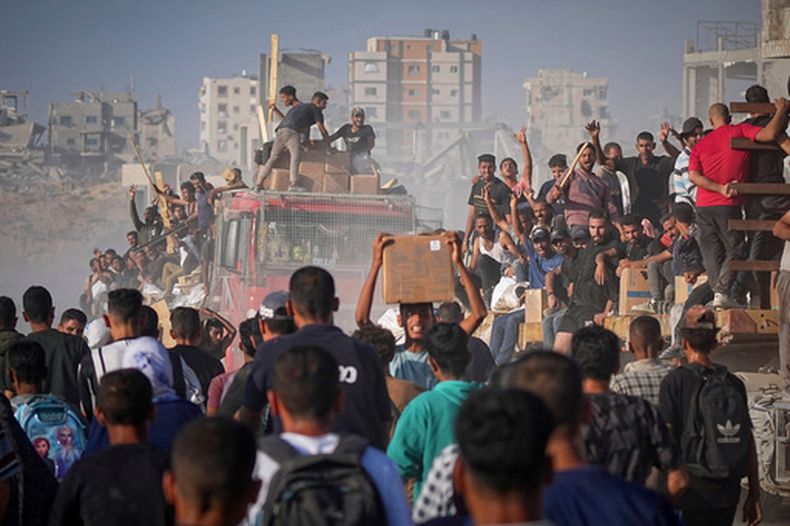 ARCHIVO - Palestinos, subidos a un camión cargado de alimentos y ayuda humanitaria del Programa Mundial de Alimentos, a su llegada al norte de la Franja de Gaza, el 16 de junio de 2025. (AP Foto/Jehad Alshrafi, archivo)