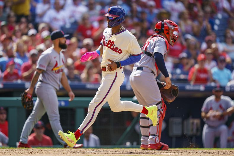 El dominicano Johan Rojas de los Filis de Filadelfia anota una carrera en la quinta entrada, mientras que el receptor venezolano de los Cardenales Wilson Contreras espera la bura durante el juego en Filadelfia. Domingo 27 de agosto de 2023. (AP Foto/Chris Szagola)