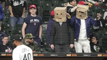Aficionados se cubren sus cabezas con bolsas de papel durante el juego de los Medias Blancas de Chicago contra los Rays de Tampa Bay, el jueves 27 de abril de 2023, en Chicago. (AP Foto/Charles Rex Arbogast)