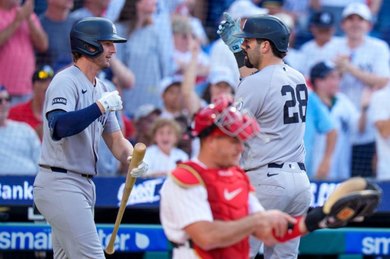 Austin Wells (derecha), de los Yankees de Nueva York, celebra su cuadrangular con Ryan McMahon (izquierda), mientras el receptor de los Filis de Filadelfia, J.T. Realmuto (centro), revisa su equipo durante la tercera entrada de un partido de béisbol, el sábado 25 de julio de 2026, en Filadelfia. (Foto AP/Chris Szagola)