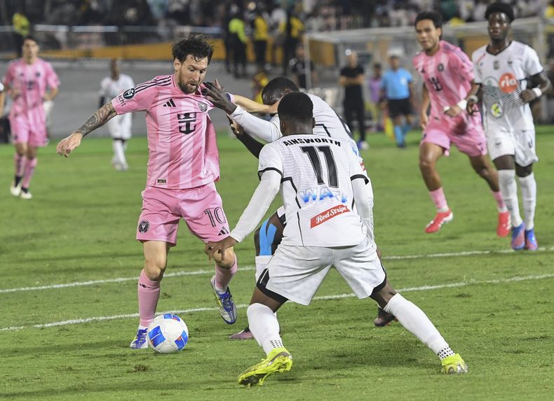 El delantero de Inter Miami Lionel Messi, a la izquierda, intenta quitarle el balón a Christopher Ainsworth, del Cavalier de Jamaica, durante un partido de fútbol de la Copa de Campeones de la CONCACAF en Kingston, Jamaica, el jueves 13 de marzo de 2025. (AP Foto/Collin Reid)