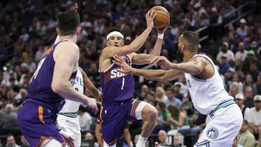 El escolta de los Suns de Phoenix, Devin Booker (1), avanza hacia la canasta mientras el pívot de los Timberwolves de Minnesota, Rudy Gobert, a la derecha, defiende durante la segunda mitad del partido de baloncesto de la NBA, el domingo 14 de abril de 2024, en Minneapolis. (AP Foto/Matt Krohn)