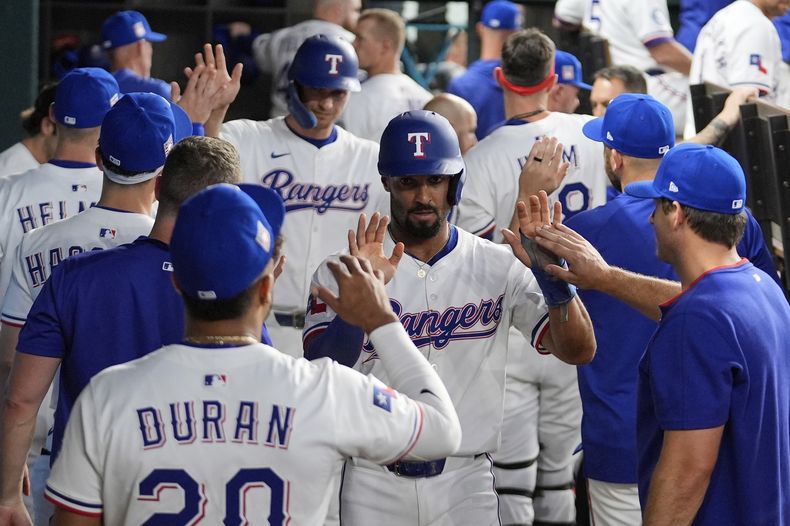Marcus Semien de los Rangers de Texas y Corey Seager celebran con sus compañeros tras anotar en el sencillo del cubano Adolis García en la tercera entrada ante los Bravos de Atlanta el sábado 26 de julio del 2025. (AP Foto/Tony Gutierrez)