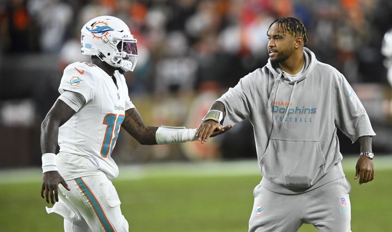 Tua Tagovailoa, derecha, de los Dolphins de Miami, felicita al también quarterback Tyler Huntley (18) mientras sale del campo durante la primera mitad del partido de la NFL en contra de los Browns de Cleveland, el domingo 29 de diciembre de 2024, en Cleveland. (AP Foto/David Richard)