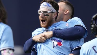 Danny Jansen, de los Azulejos de Toronto, es abrazado por su compañero de equipo Matt Chapman después de batear sencillo productor de dos carreras para ganarle a los Bravos de Atlanta, durante la novena entrada del juego de béisbol, en Toronto, el domingo 14 de mayo de 2023. (Frank Gunn/The Canadian Press vía AP)