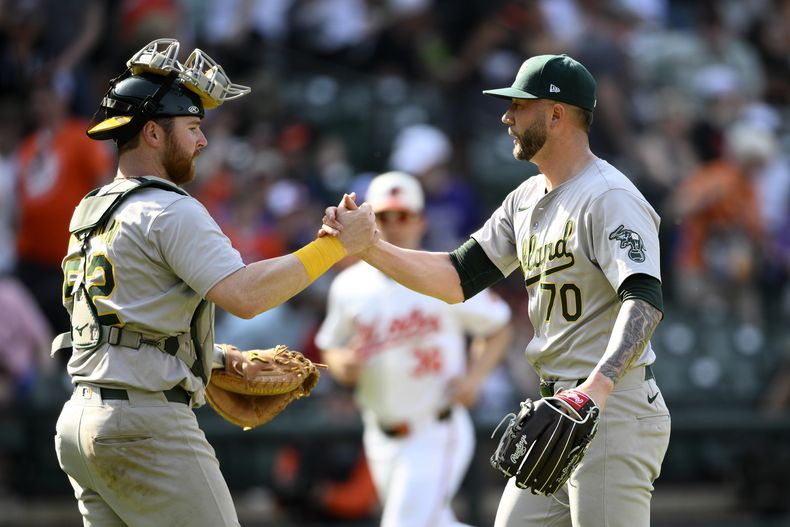 El relevista de los Atléticos de Oakland Lucas Erceg celebra con el cátcher Kyle McCann (52) la victoria en el juego ante los Orioles de Baltimore el domingo 28 de abril del 2024. (AP Foto/Nick Wass)