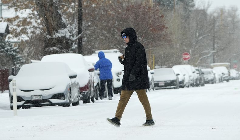 Un peatón cruza la Primera Avenida mientras una tormenta invernal azota el oeste intermontano, desplomando las temperaturas y trayendo consigo una ligera nevada a su paso el sábado 18 de enero de 2025, en Denver. (AP foto/David Zalubowski)