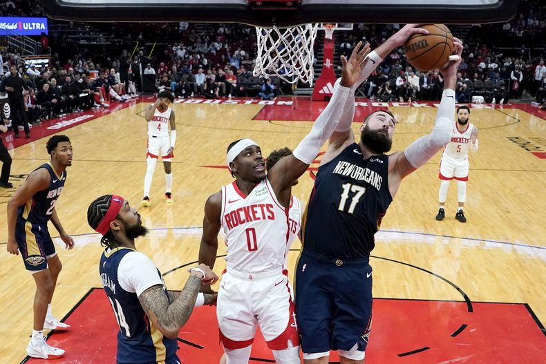 El lituano Jonas Valanciunas, de los Pelicans de Nueva Orleáns, atrapa un rebote junto a Aaron Holiday, de los Rockets de Houston, el miércoles 31 de enero de 2024 (AP Foto/Eric Christian Smith)