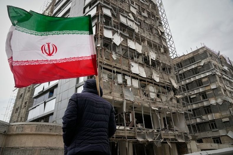 Un hombre sujeta una bandera iraní tras un ataque en Teherán, Irán, el 2 de marzo del 2026. (AP foto/Vahid Salemi)